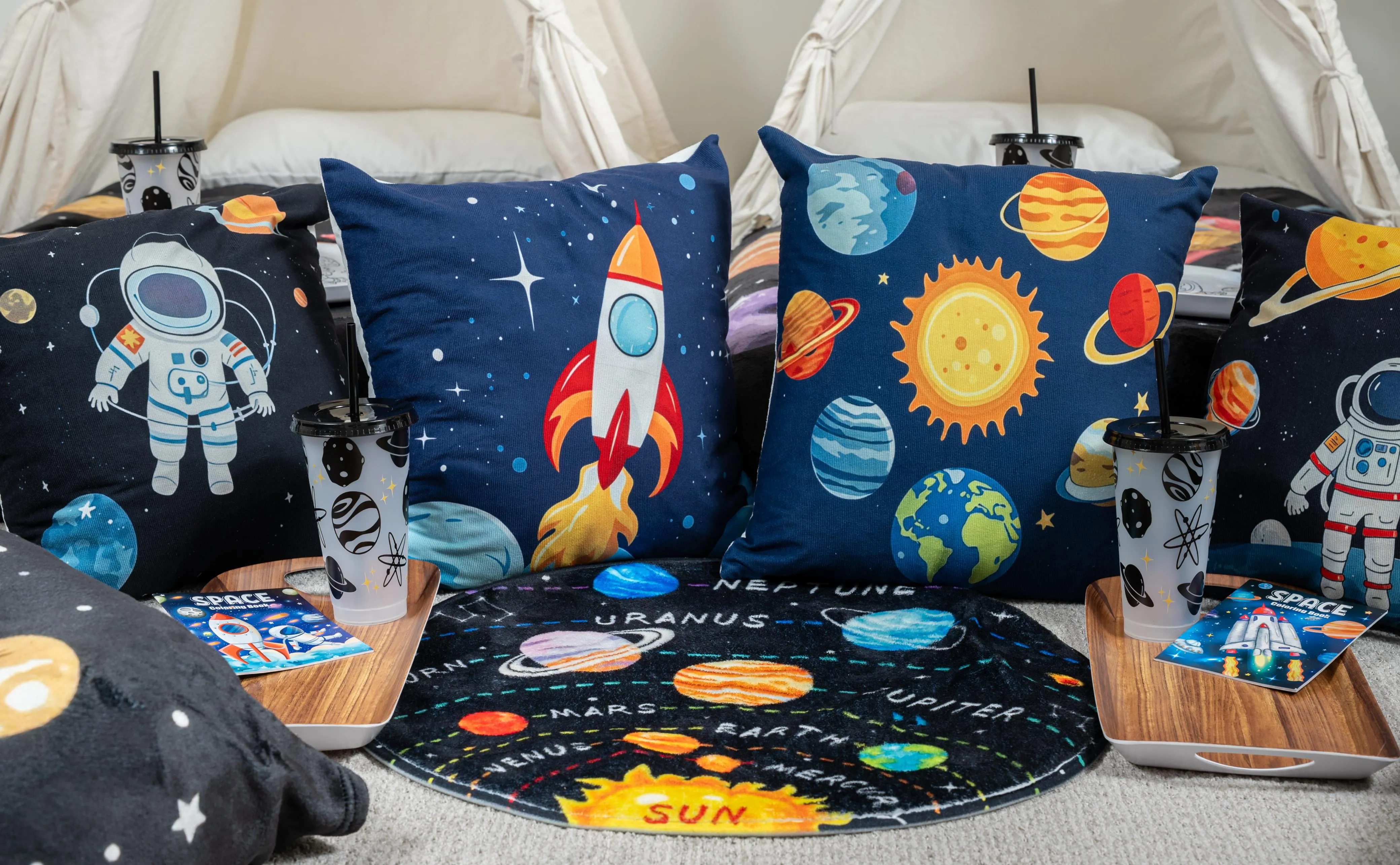 Close view of astronaut and planet pillows with space-print bedding and trays.